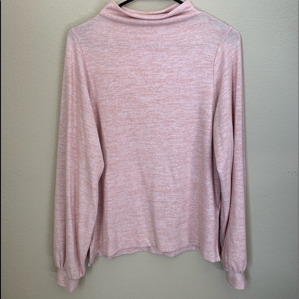 A pink turtleneck sweater with cuffed sleeves